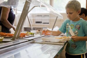 boy in green crew neck t-shirt standing in front of food on table