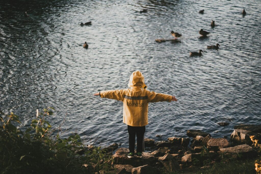 person standing on rock boulder beside body of water