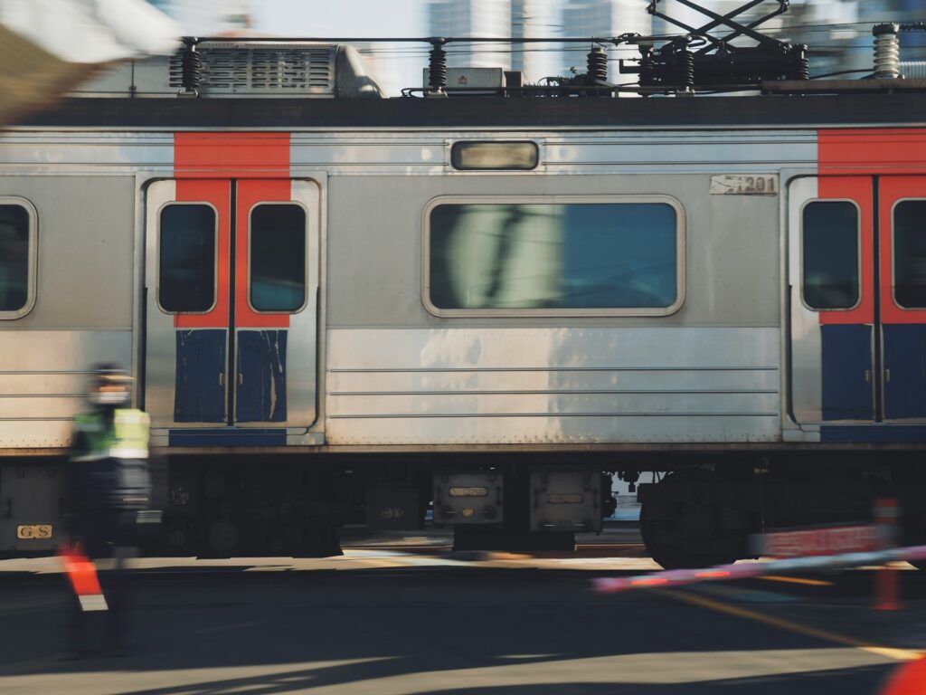 a silver train traveling down train tracks next to a tall building